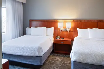 a hotel room with two beds and a night stand at Courtyard Cincinnati Blue Ash in Blue Ash