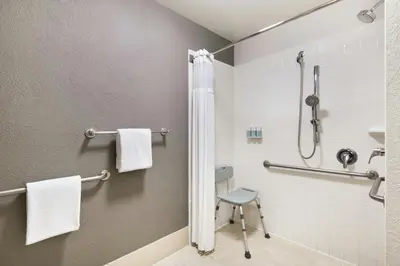 a bathroom with a shower and a chair at Courtyard Cincinnati Blue Ash in Blue Ash