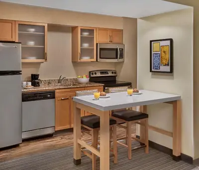 a kitchen with a table with two bar stools at Sonesta ES Suites Cincinnati - Blue Ash in Blue Ash