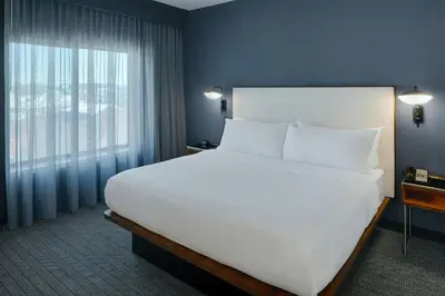 a large white bed in a room with a window at Courtyard Dayton South Mall in Miamisburg