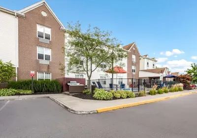 a building with a fence in front of a street at Birch Hills Suites - Blue Ash in Blue Ash