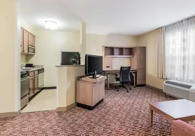 a hotel room with a kitchen and a desk with a computer at Birch Hills Suites - Blue Ash in Blue Ash