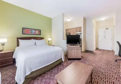 a hotel room with a bed and a flat screen tv at Birch Hills Suites - Blue Ash in Blue Ash