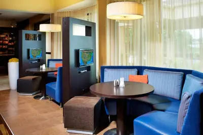 a restaurant with blue chairs and a table and tables at Courtyard by Marriott Lexington North in Lexington
