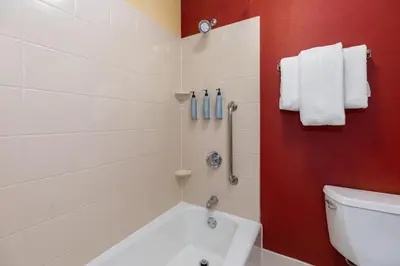 a bathroom with a white tub and a red wall at Courtyard Toledo Airport Holland in Holland