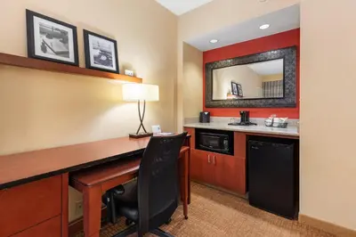 a hotel room with a desk and a mirror at Courtyard Toledo Airport Holland in Holland