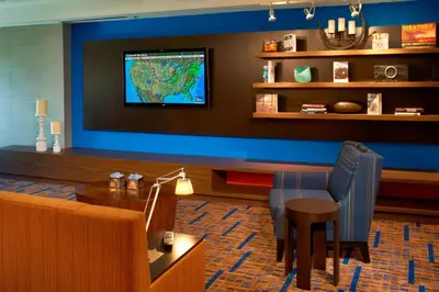 a waiting room with a table and a tv on a wall at Courtyard Toledo Rossford/Perrysburg in Rossford
