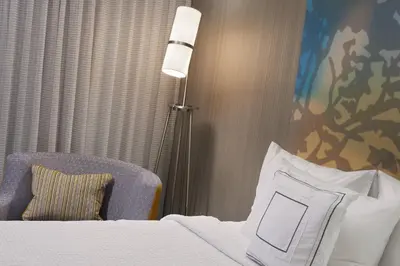 a hotel room with a bed and a lamp and a chair at Courtyard Toledo Maumee/Arrowhead in Maumee