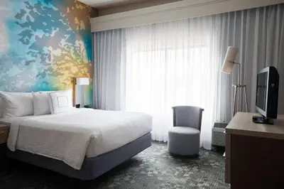 a bedroom with a bed and a tv and a chair at Courtyard Toledo Maumee/Arrowhead in Maumee