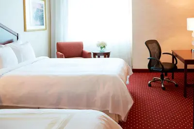 a hotel room with two beds and a desk and a chair at Columbus Airport Marriott in Columbus