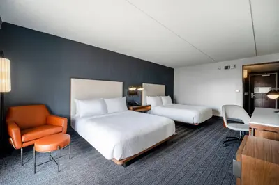 a hotel room with two beds and a chair at Courtyard Columbus Airport in Columbus