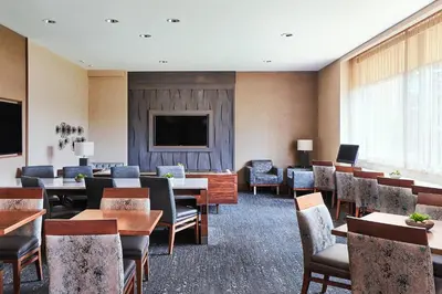 a waiting room with tables and chairs and a flat screen tv at Cleveland Marriott East in Warrensville Heights