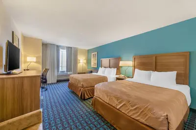 a hotel room with two beds and a flat screen tv at Quality Inn & Suites Sandusky in Sandusky