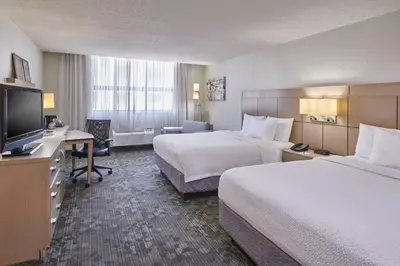 a hotel room with two beds and a desk and a television at Courtyard Columbus Downtown in Columbus