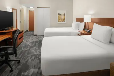 a hotel room with two beds and a desk and a television at Fairfield Inn & Suites Columbus OSU in Columbus