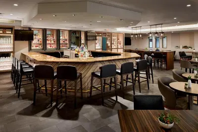 a restaurant with a bar with chairs and tables at Marriott Cincinnati Airport in Hebron