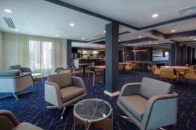 a waiting room with chairs and tables in a hotel at Courtyard by Marriott Cincinnati Airport in Erlanger