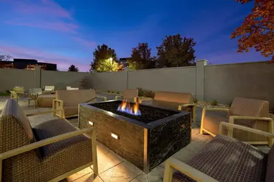 a patio with a fire pit and chairs and a fence at Courtyard by Marriott Cincinnati Airport in Erlanger