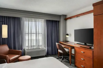 a hotel room with a bed and a desk with a television at Courtyard Hamilton in Hamilton