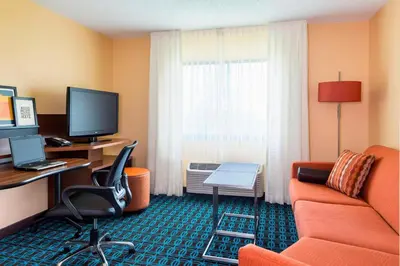 a hotel room with a couch and a desk with a computer at Fairfield Inn & Suites Springfield in Springfield