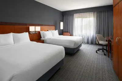 a hotel room with two beds and a desk at Courtyard Dayton-University of Dayton in Dayton