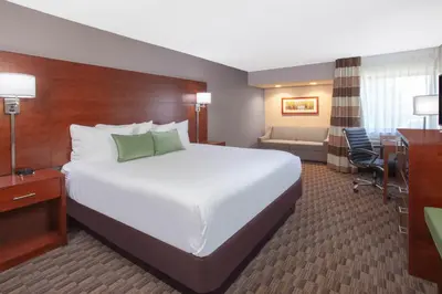 a hotel room with a large bed and a desk at Wyndham Garden Fort Wayne in Fort Wayne