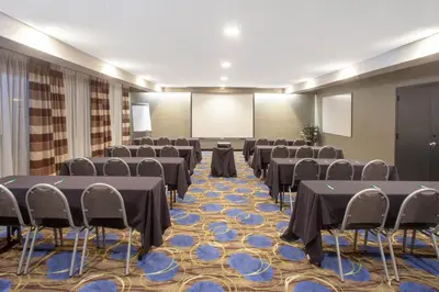 a conference room with tables and chairs and a screen at Wyndham Garden Fort Wayne in Fort Wayne