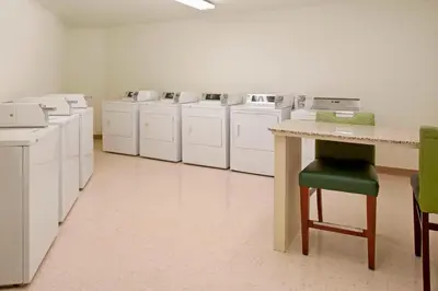 a laundry room with white washes and a green chair at Residence Inn by Marriott Fort Wayne Southwest in Fort Wayne