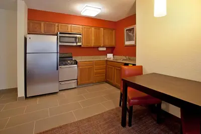 a kitchen with a stainless steel refrigerator and wooden cabinets at Residence Inn by Marriott Fort Wayne Southwest in Fort Wayne