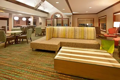 a hotel lobby with a couch and tables and chairs at Residence Inn by Marriott Fort Wayne Southwest in Fort Wayne