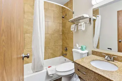 a bathroom with a toilet and a sink and a tub at Econo Lodge Akron Copley Northwest in Montrose