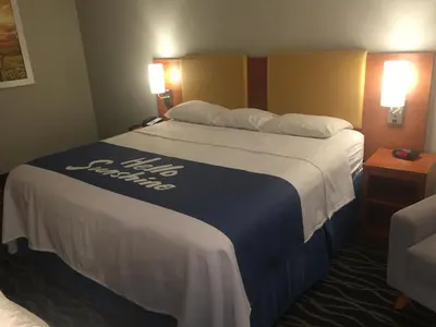 a hotel room with a large bed with a blue and white blanket at Days Inn & Suites by Wyndham Cincinnati North in Springdale