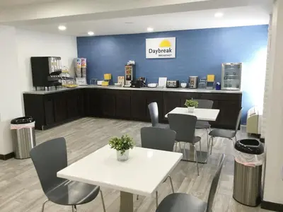 a restaurant with tables and chairs and a counter at Days Inn & Suites by Wyndham Cincinnati North in Springdale