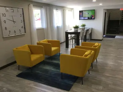 a waiting room with yellow chairs and a clock at Days Inn & Suites by Wyndham Cincinnati North in Springdale