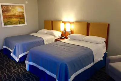 a hotel room with two beds and a couch at Days Inn & Suites by Wyndham Cincinnati North in Springdale