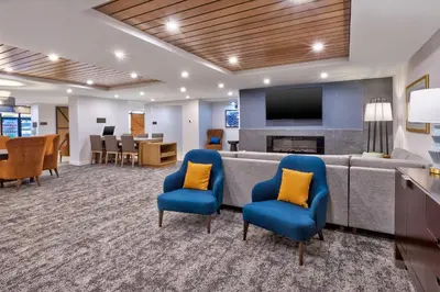a waiting room with a couch and chairs and a tv at Staybridge Suites Pittsburgh Airport by IHG in Pittsburgh