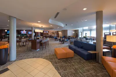 a lobby of a hotel with tables and chairs at Courtyard by Marriott Canton in North Canton