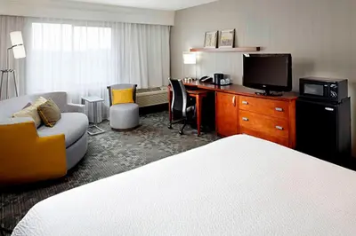 a hotel room with a bed and a desk with a television at Courtyard by Marriott Akron Stow in Stow