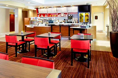 a restaurant with red chairs and tables and a counter at Courtyard by Marriott Akron Stow in Stow