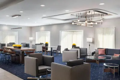 a lobby with chairs and tables and a chandelier at Courtyard Cleveland Beachwood in Beachwood