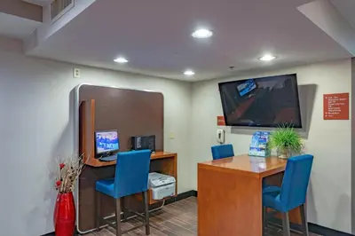 an office with a desk and two blue chairs and a tv at TownePlace Suites Cleveland Streetsboro in Streetsboro