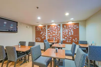 a dining room with tables and chairs and a large screen at TownePlace Suites Cleveland Streetsboro in Streetsboro