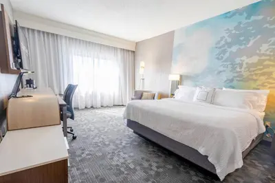 a hotel room with a large bed and a desk at Courtyard by Marriott Cleveland Willoughby in Willoughby