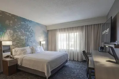 a hotel room with a bed and a desk with a television at Courtyard by Marriott Cleveland Willoughby in Willoughby