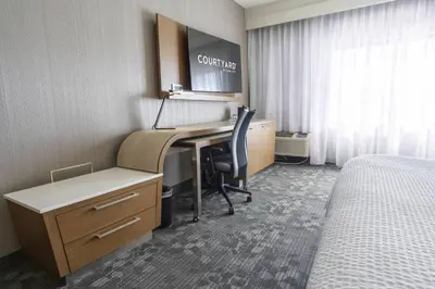 a hotel room with a desk and a bed at Courtyard by Marriott Cleveland Willoughby in Willoughby