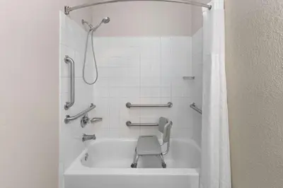 a bathroom with a tub with a chair in it at Wingate by Wyndham Marion in Marion