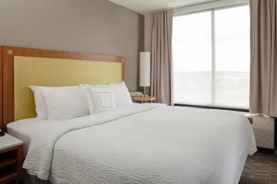 a bedroom with a white bed with a large window at SpringHill Suites Cincinnati North Forest Park in Springdale