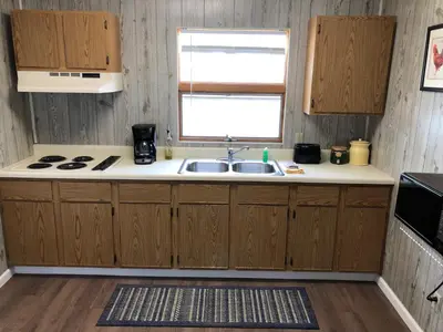 a kitchen with wooden cabinets and a sink and a window at Little Ted's Cottages in Marblehead