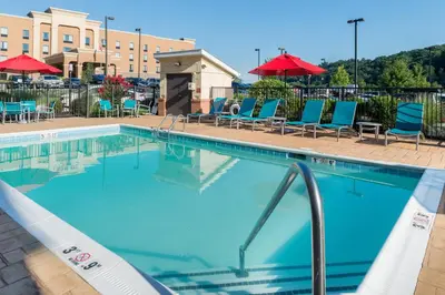 a swimming pool at a hotel with chairs and umbrellas at TownePlace Suites Huntington in Huntington