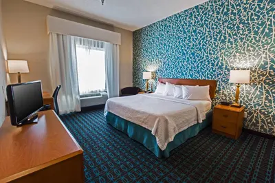 a hotel room with a bed and a flat screen tv at Fairfield Inn & Suites Toledo North in Toledo
